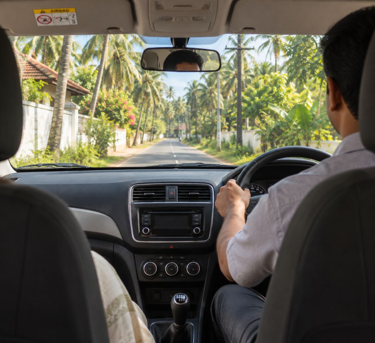 A driver on a palm-lined Kerala road, seen from the back seat